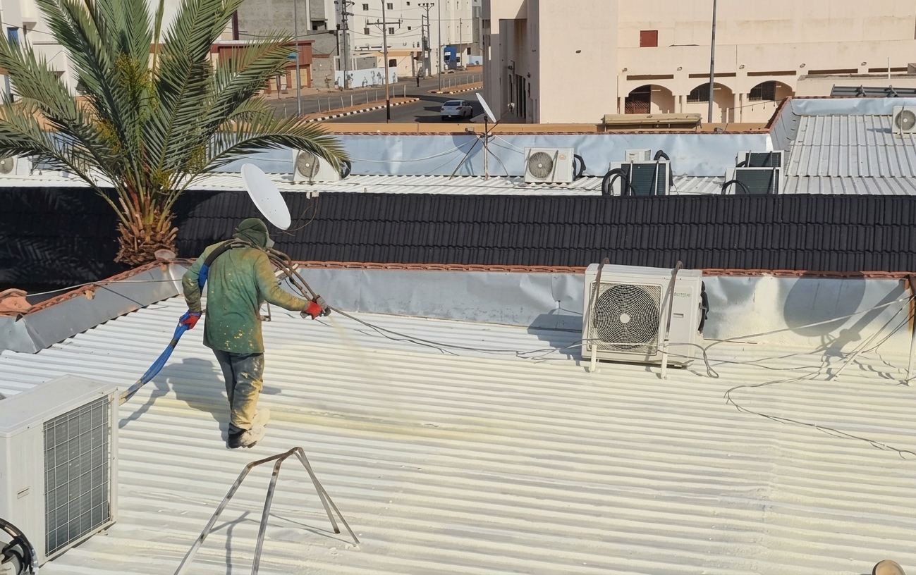 عامل يطبق عزل الفوم على سطح مبنى في موقع عمل